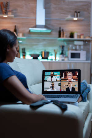 Woman freelancer having web chat conference sitting on sofa in living room. Remote worker discussing...