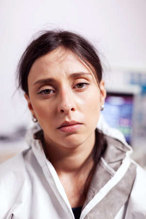 Portrait of tired dentist in protective gear agasint coronavirus looking at camera. Exhausted...
