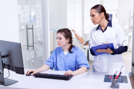 Dentist and nurse in in stomatolog office reception looking at s Stomatology assistant and teeth...