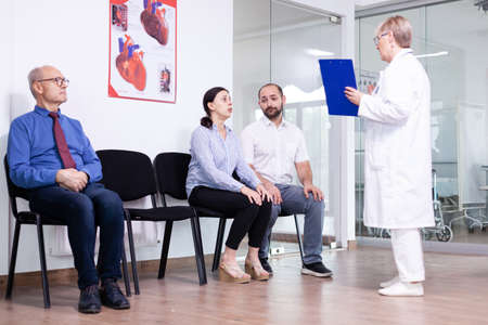 Woman crying looking at doctor after unfavorable news in hospital waiting area. Stressed man and woman during medic appointment. Man leaving clinic.の写真素材