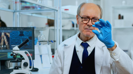 Mature man lab technician looking at virus sample in modern equipped laboratory. Scientist working with various bacteria tissue and blood tests, concept of pharmaceutical research for antibioticsの写真素材
