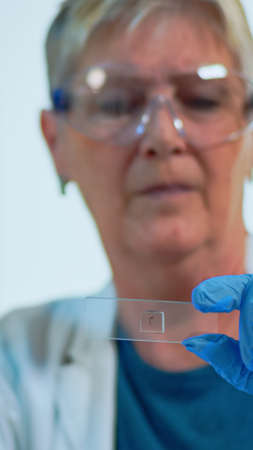 Close up of woman lab engineer analysing virus samples in modern equipped laboratory. Senior doctor...