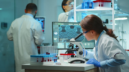 Microbiologist working late at night for new vaccine in modern laboratory looking at samples under...