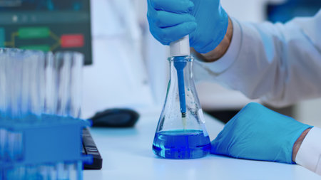 Close up of scientist filling test tube with liquid using pipette in equipped laboratory. Scientist...