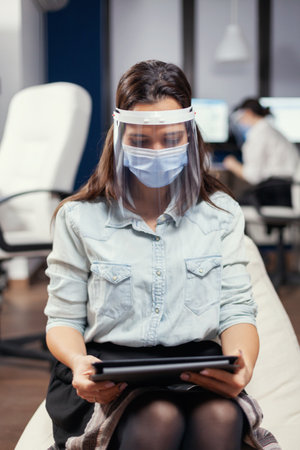 Woman entrepreneur wearing face mask against covid19 as safety precaution. Multiethnic business team working respecting social distance during global pandemic with covid-19.の写真素材