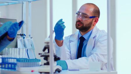 Doctor dictating to nurse virus results informations looking on test tubes in modern equipped...