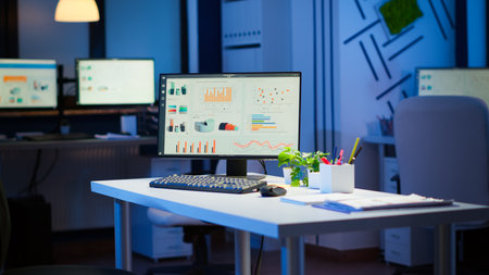 Empty start up business office with modern design during night with graphics running on the desktop....