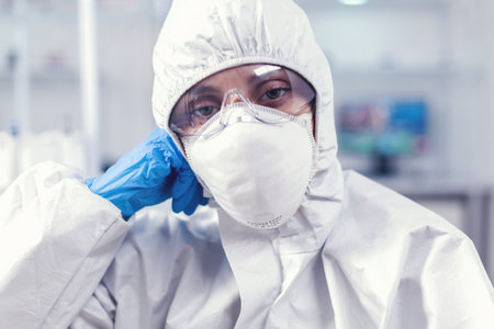 Portrait of overworked biolog looking at camera in modern equipped lab. Tired woman scientist in...