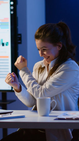 Excited woman feel ecstatic reading great online news on laptop working overtime in start up company office. Happy employee using modern technology network wireless studying writing, searchingの写真素材