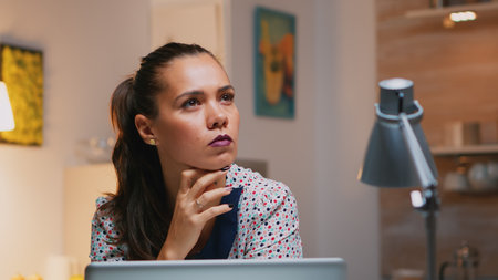 Portrait of businesswoman thinking of email answer working at home sitting on kitchen desk. Close up...