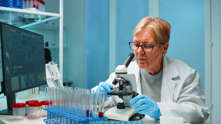 Woman research scientist looking at samples under microscope in modern equipped laboratory in the night. Working with various bacteria, tissue and blood tests, pharmaceutical research for antibioticsの写真素材