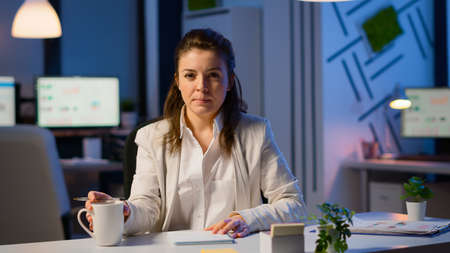 Businesswoman discussing during video conference working at midnight sitting in workplace late at...