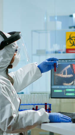 Biotechnology scientist wearing ppe suit researching in equipped laboratory. Chemists examining...