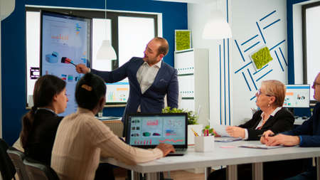 Business partner presenting company strategy to diverse team brainstorming in new startup office,...