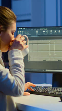 Freelancer architect working in 3D software to elaborate container design sitting at desk in...