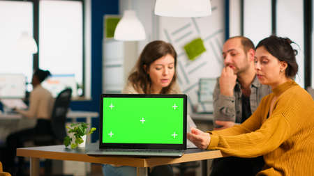 Group of business people discussing company plan with mockup laptop in front of camera, pc ready for financial project presentation placed on desk. Leader using green screen pc with chroma key displayの写真素材