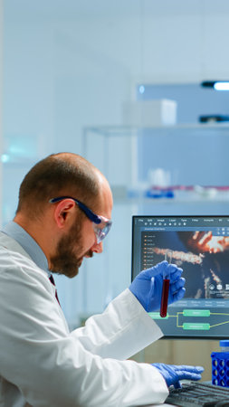 Laboratory medical stuff disscussing about vaccine development holding test tube with blood sample. Medical scientist working with DNA scan image in modern equipped laboratory using high techの写真素材