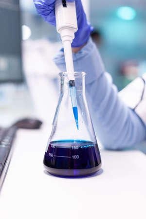 Close up of micropipette dipping in test tube for science experiment. Pharmacy scientist doctor...