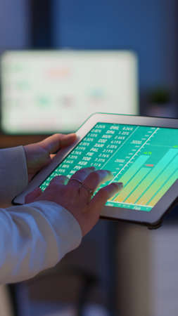 Close-up photo of woman hands holding tablet computer analysing graphs standing in start-up office...
