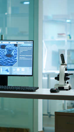 Modern empty biological applied science laboratory with technological microscopes, glass test tubes, micropipettes, desktop computers and displays. PCs are running sophisticated DNA calculations.の写真素材