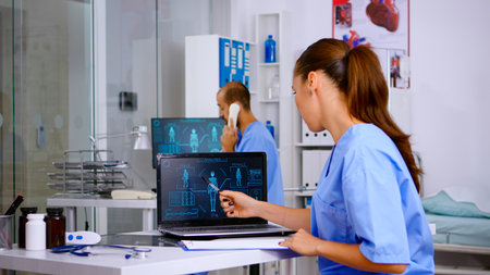 Student medical practitioner analysing human body digital scan, holding radiography sitting in hospital. Radiologist in medicine uniform looking at x-ray, examination, bone, practitioner, diagnosis.の写真素材