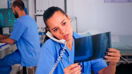 Assistant explaining to patient, talking at phone, the result of x-ray offering treatment for...