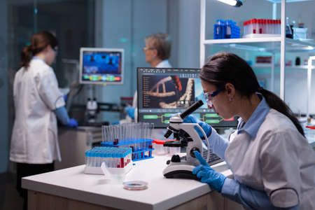 Biochemist scientists studying reaction of virus on microscope in laboratory. Research chemists working in lab with high tech analyzing blood and genetic material samples with special programの写真素材