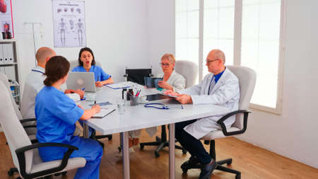 Young nurse explaining diagnosis to medical staff in hospital conference room and having discussion about symptoms of patients. Clinic expert therapist talking with colleagues , medicine professionalの写真素材