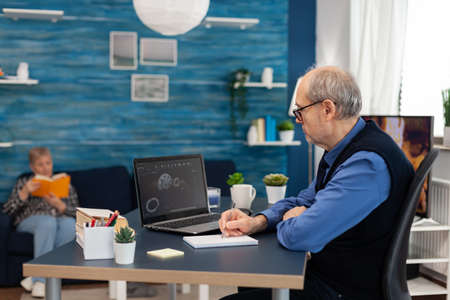 Experienced technician taking notes designing gear system. Engineer working from home office on...