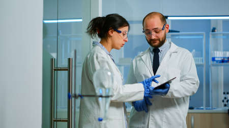 Scientist team meeting and discusssing treatment results standing in research laboratory pointing on...