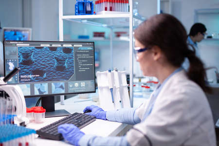 Woman biotechnology scientist working at computer researching in development laboratory. Chemistry research technology in science medicine lab developing and stying new type of vaccineの写真素材