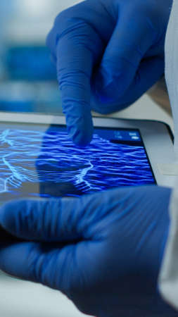 Close up of chemist doctor working on tablet with DNA scan image analysing treatment results....