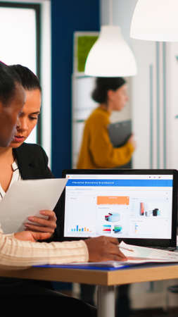 Diverse business people, company staff group, sitting at desk in modern office, discussing about...