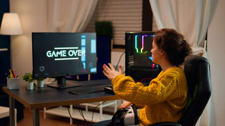 Gamer woman losing videogame tournament while playing with VR headset using joystick controller and...