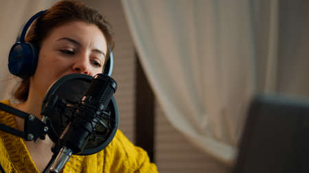Woman checking sound before recording live podcast in home studio. Lady presenter making video...