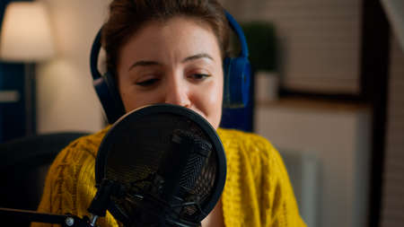 Influencer talking on professional microphone during livestreaming recording vlog in living room. On-air online production internet broadcast show host streaming live content for social mediaの写真素材