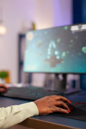 Professional e-sport gamer playing online games in home living room. Close up of african woman hand...