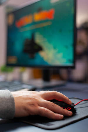Close up hand of pro gamer in home studio using professional mouse, streaming online gaming tournament. Playing virtual first space shooter video gameの写真素材
