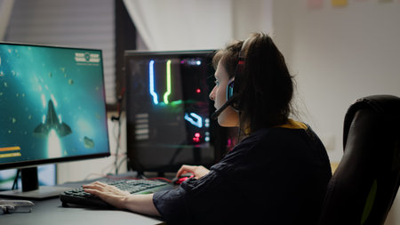 Pro woman video game r using headset and powerful computer playing online space shooter video games in gaming room. Virtual streaming cyber wearing headphones performing online tournamentの写真素材