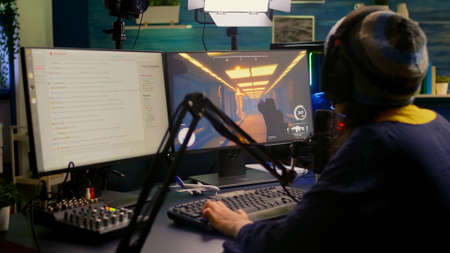 Pro streamer check sound on mixer and start playing first person shooter video game during virtual...