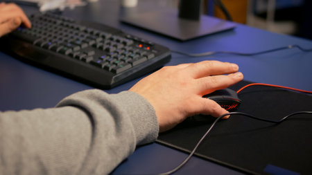 Close-up on hands of player man using professional RGB mouse and keyboard. Digital gamer using...