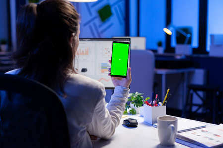 Freelancer looking at mobile phone with green screen display during online videocall meeting sitting...