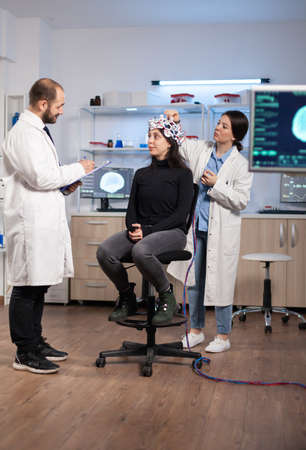 Professional neurological researcher explaning treatment result while medical scientist adjusting...