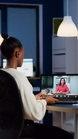 African freelancer working remotely discussing with woman partner online sitting in front of laptop...
