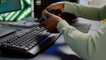 Close-up of professional cyber gamer holding joystick playing space shooter video game. Pro player...