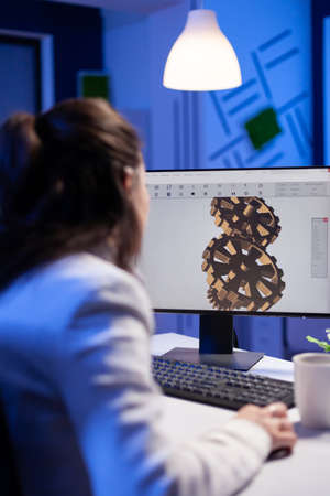 Focused architect working at new project using computer doing gear prototype late at night sitting...