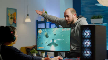 Nervous man screaming at woman while she is playing space shooter video game on RGB powerful...