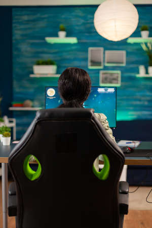 Back view of black woman playing online space shooter game. Competitive cyber player woman...