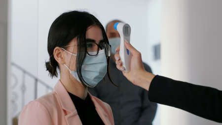 Close up of freelancer measure collegues temperature using medical thermometer to protect...