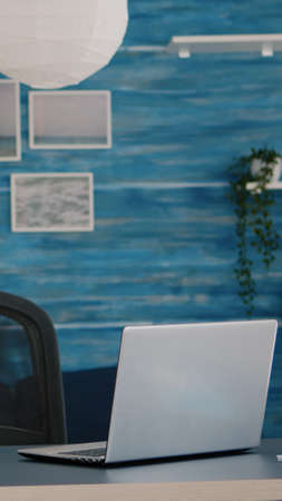 Empty home office with computer in a beautiful, spacious living room interior with blue furniture and walls. Workplace with nobody in it, place of work, workspace concept, pretty simple modern decorの写真素材